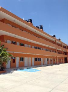 an orange building with a palm tree in front of it at Paraiso del Pescador in Rincon de Guayabitos