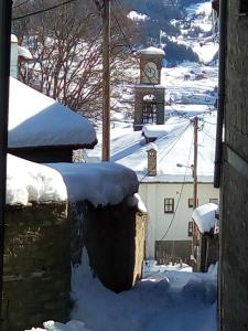 un bâtiment avec une tour d'horloge dans la neige dans l'établissement To Patriko Tou Saranti, à Metsovo