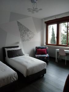 a bedroom with two beds and a chair and window at B&B Xenia in Pordenone