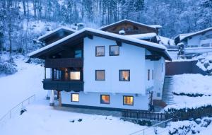 ein Haus im Schnee mit eingeschaltetem Licht in der Unterkunft Apart Sunnseitn in Bruck am Ziller