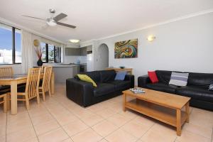 a living room with a black couch and a table at Spindrift on the Beach - Absolute Beachfront in Gold Coast