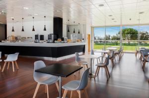 un restaurant avec des tables, des chaises et un comptoir dans l'établissement B&B HOTEL Cantanhede Coimbra, à Cantanhede