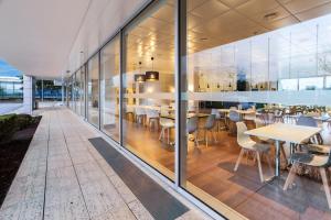 um restaurante com paredes de vidro, mesas e cadeiras em B&B HOTEL Cantanhede Coimbra em Castanhede