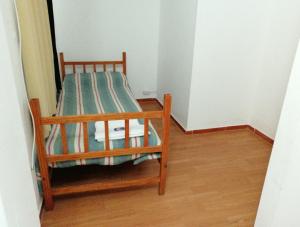 a small bed in a room with a wooden floor at Departamento Familiar Centro in San Agustín de Valle Fértil