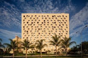 a large white building with palm trees in front of it at B Hotel Brasilia in Brasília