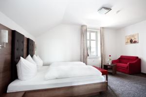 Gasthaus Bürger-Stube في ساسباخ آم كايزرشتول: غرفة نوم بسرير ابيض وكرسي احمر