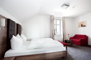 a bedroom with a white bed and a red chair at Gasthaus Bürger-Stube in Sasbach am Kaiserstuhl