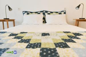 uma cama com uma colcha azul e amarela em AZORESTAY em Horta