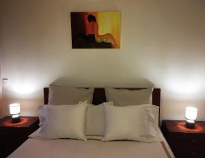 uma cama com almofadas brancas e um quadro na parede em Love Sea Apartment em Leça da Palmeira