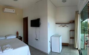 a bedroom with a bed and a tv on the wall at Pousada Cruzeiro do Sul in São Miguel do Gostoso