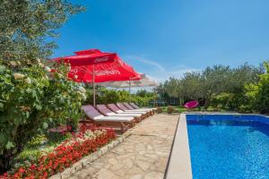 ein Pool mit einem roten Sonnenschirm und Stühlen neben einem Pool in der Unterkunft New modern dream villa 2019 in Kreševo