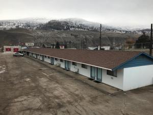 una fila de edificios en un estacionamiento con una montaña en Tumbleweed Motel, en Cache Creek