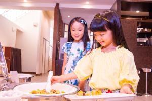 Duas raparigas na cozinha a preparar comida. em Kanucha Bay Hotel & Villas em Nago
