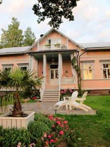 uma casa cor-de-rosa com um banco à frente. em Hotel Töyrylä Manor em Artjärvi