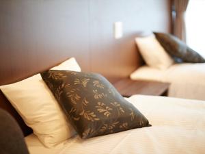 a bed with a brown pillow on top of it at Creass Hotel Tsubogawa Marche in Naha