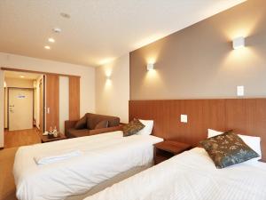 ein Hotelzimmer mit 2 Betten und einem Sofa in der Unterkunft Creass Hotel Tsubogawa Marche in Naha