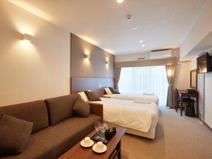 Habitación de hotel con 2 camas y sofá en Creass Hotel Tsubogawa Marche en Naha