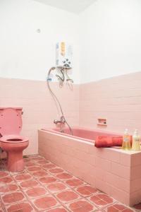 W łazience znajduje się różowa wanna i różowa toaleta. w obiekcie Rumah Larasati w mieście Malang