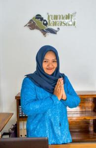 a woman in a blue hijab is praying at Rumah Larasati in Malang