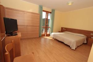 Schlafzimmer mit einem Bett und einem Flachbild-TV in der Unterkunft Park Hotel Faver in Tremosine sul Garda