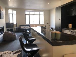a living room with a kitchen with a counter and chairs at Bond Street Apartment Luxury 3 Bedroom in Dunedin