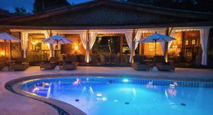 a swimming pool with umbrellas and a house at Beyond The Blue Horizon Boutique Bungalows in Haad Chao Phao