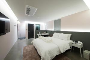 Un dormitorio con una gran cama blanca y un televisor. en HOTEL H, en Seúl