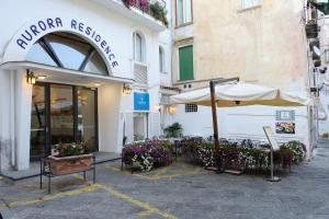 een restaurant met een parasol, stoelen en bloemen bij Aurora Apartments in Amalfi