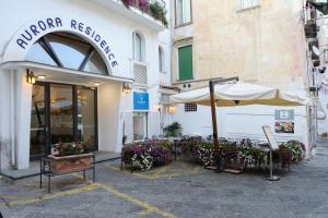 a restaurant with an umbrella and chairs and flowers at Aurora Residence in Amalfi