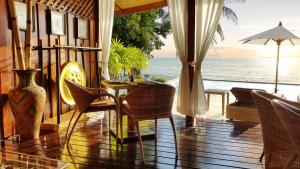 a porch with a table and chairs and the ocean at Beyond The Blue Horizon Boutique Bungalows in Haad Chao Phao