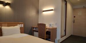 una camera d'albergo con letto e scrivania con sedia di Ueno First City Hotel a Tokyo