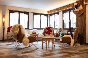 a room with a bunch of chairs and windows at Hotel Daniela in Zermatt