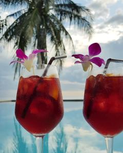 two cocktails in glasses next to a swimming pool at Beyond The Blue Horizon Boutique Bungalows in Haad Chao Phao