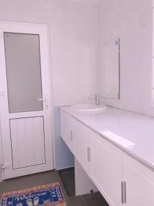 a white bathroom with a sink and a mirror at Sleep Box Hostel Phú Quốc in Phú Quốc