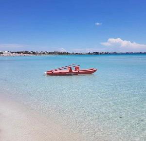 ein rotes Boot im Wasser neben einem Strand in der Unterkunft Al Ponte in Torre Lapillo