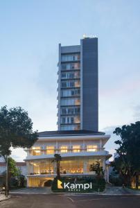Kampi Hotel Tunjungan - Surabaya في سورابايا: مبنى طويل مع علامة أمامه
