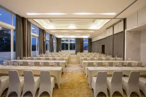 uma sala de conferências com mesas e cadeiras brancas em Kampi Hotel Tunjungan - Surabaya em Surabaia