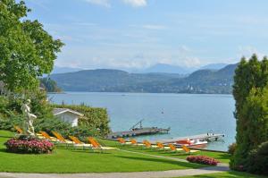 a row of lounge chairs and a dock on a lake at Dermuth Hotels – Hotel Dermuth Pörtschach in Pörtschach am Wörthersee