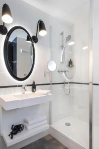 La salle de bains est pourvue d'une douche, d'un lavabo et d'un miroir. dans l'établissement Aparthotel Adagio Paris Montmartre, à Paris