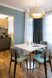 une salle à manger avec une table et des chaises blanches dans l'établissement Aparthotel Adagio Paris Montmartre, à Paris