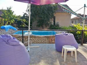 a pool with two purple chairs and an umbrella at Guest House Bedrock in Belogradchik