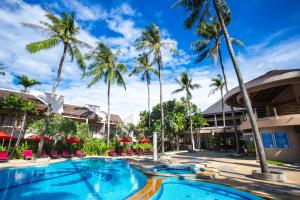 a swimming pool at a resort with palm trees at Coconut Village Resort Phuket - SHA Extra Plus in Patong Beach