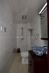a bathroom with a toilet and a sink with a bowl at Qianmen Courtyard Hotel in Beijing