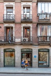 un grupo de personas caminando en una calle frente a un edificio en Hostal Cervelo, en Madrid