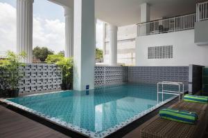 a swimming pool in a building with two chairs at KHAS Tugu Hotel Yogyakarta in Yogyakarta