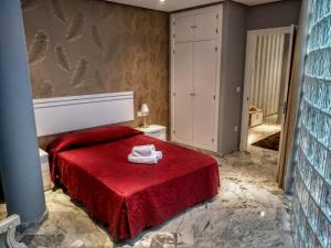 sypialnia z czerwonym łóżkiem i czerwonym kocem w obiekcie Apartamentos El Vestuario w Kadyksie