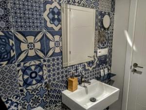 W łazience znajduje się umywalka oraz ściany wyłożone niebiesko-białymi kafelkami. w obiekcie Apartamentos El Vestuario w Kadyksie