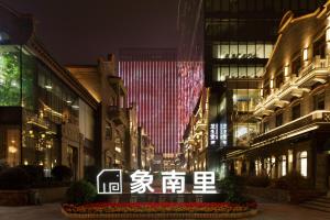 Hyatt House Chengdu Pebble Walk في تشنغدو: شارع المدينة في الليل مع مبنى به أضواء