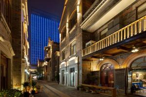 an alley in a city at night with a blue building at Hyatt House Chengdu Pebble Walk in Chengdu