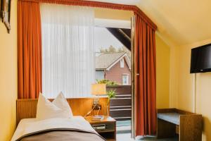a bedroom with a bed and a large window at Hotel Achtermann in Braunlage